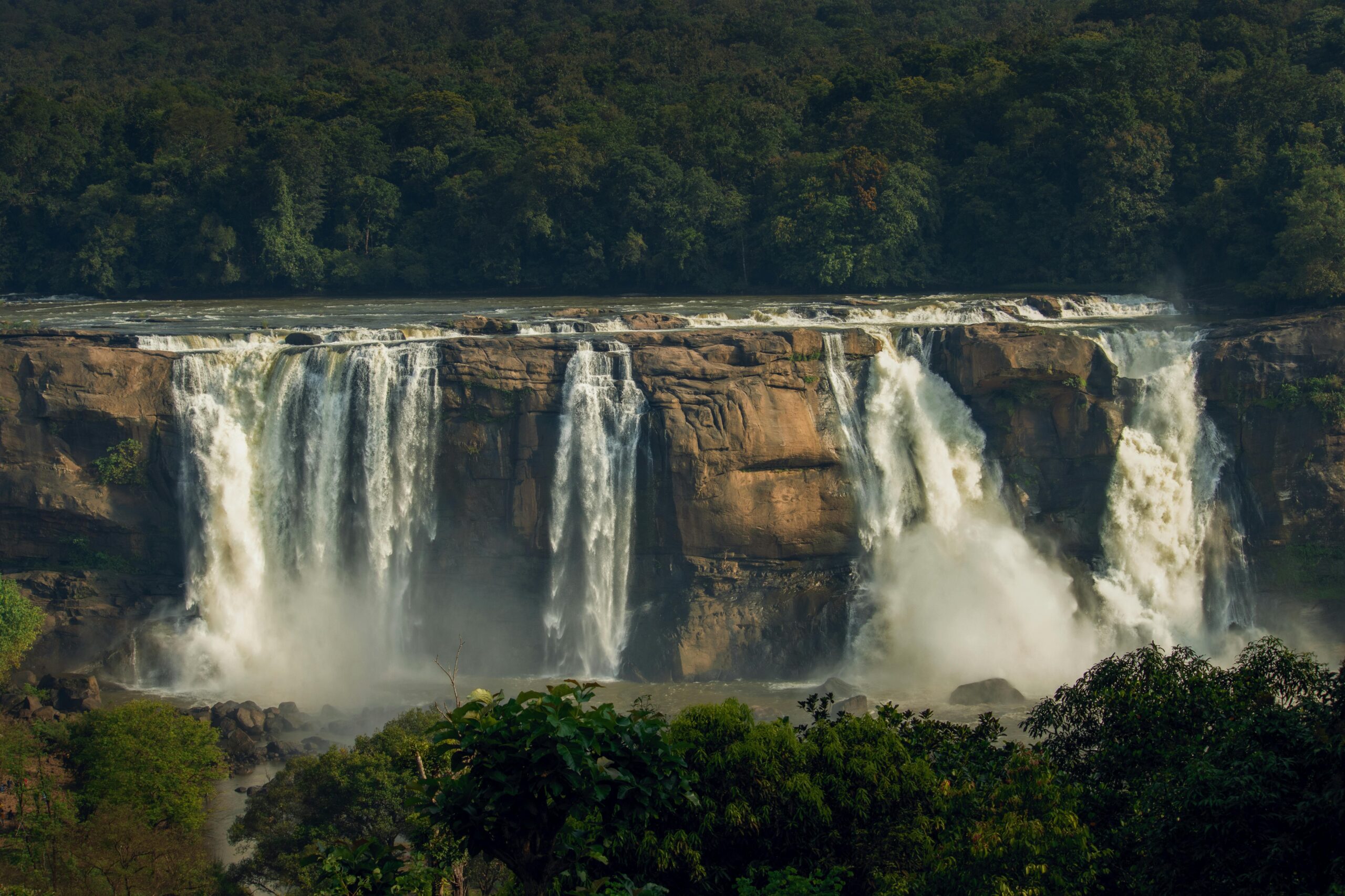 Stunning view of Athirappilly Waterfall in Pariyaram, Kerala, surrounded by lush greenery.