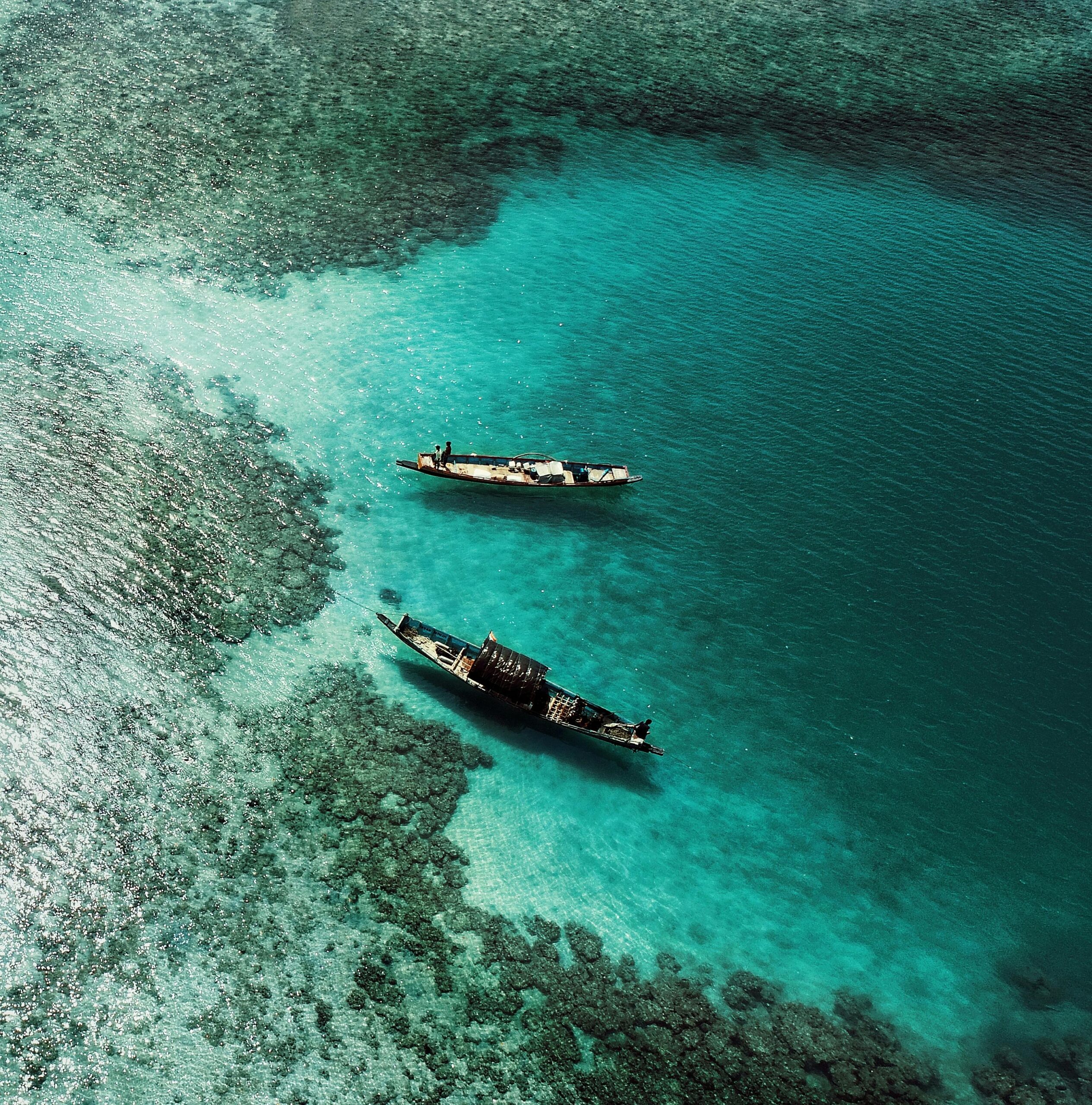 Aerial photograph showcasing two boats on the turquoise waters near coral formations in the Andaman Sea.